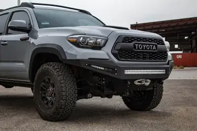 Addictive Desert Designs HoneyBadger front bumper with winch mount and 30 Universal LED bar mounts with HB logo cutout with 10 SR Rigid bar mounts in side panels in Hammer Black with Satin Black panels